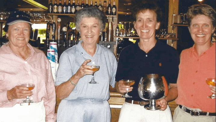 4 women smiling and holding trophy